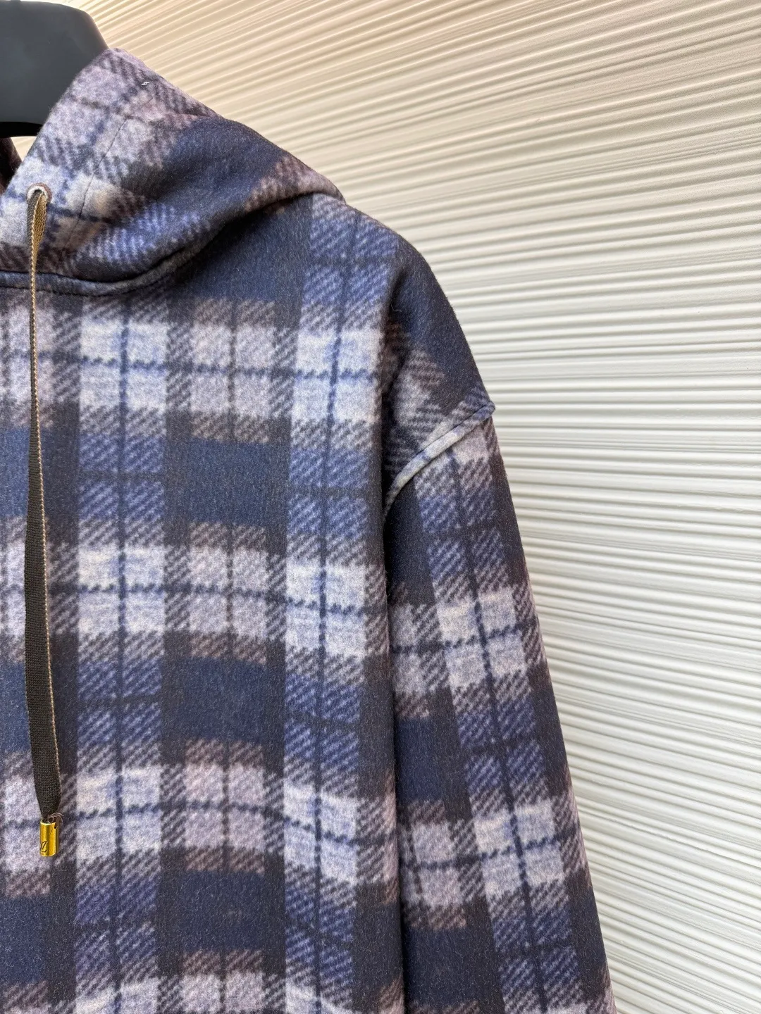 LOUIS VUITTON plaid gradient long-sleeved hoodie ●Original version: Purchased and developed for 15100 ●Item number: 1681896-B40 ●Fabric: wool blended fabric ●Technology: Digital direct printing ●Color: Purple ●Version: Fitted version ●Weight: about 1035 grams ●Size: S-M-L-XL ●Description: This hooded sweatshirt uses splicing technology to create a layered texture: the upper part is made of wool blended fabric with a blue and gray plaid pattern, and is pre-shrunk to ensure a stable fit; the lower part and sleeves use digital printing technology to present a gradient Monogram dark pattern, and the ink penetrates the fiber to achieve high color fastness. The hood has a built-in invisible lining to enhance stiffness, and the drawstring is made of wear-resistant nylon rope with a metal bell for smooth pulling. The front kangaroo pocket is made of welted bag technology, and the edge of the bag mouth is reinforced with double stitching. The cuffs and hem are made of ribbed knitted fabric, and the elastic hemming fits the body shape. The seams throughout the garment are high-strength stitches of the same color. Precision sewing every 3cm/12 stitches improves durability. The overall craftsmanship takes into account both visual details and practical durability. The overall wiring is straight and delicate, the fabric is comfortable and soft, and the color is consistent without color difference. It can be matched with the same style to create a fashionable look and control various occasions. Customized accessories, complete with three standards, same style for men and women!